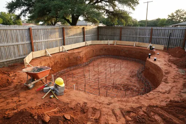 New gunite pool under construction in Texas: rebar grid and plumbing stubs in the excavated shell